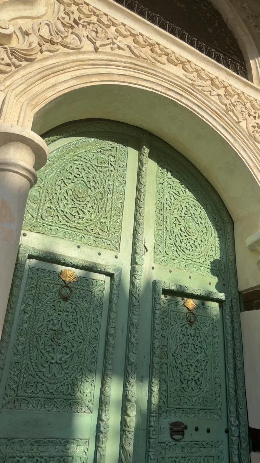 باب أخضر مزخرف تحيط به زخارف وقوس